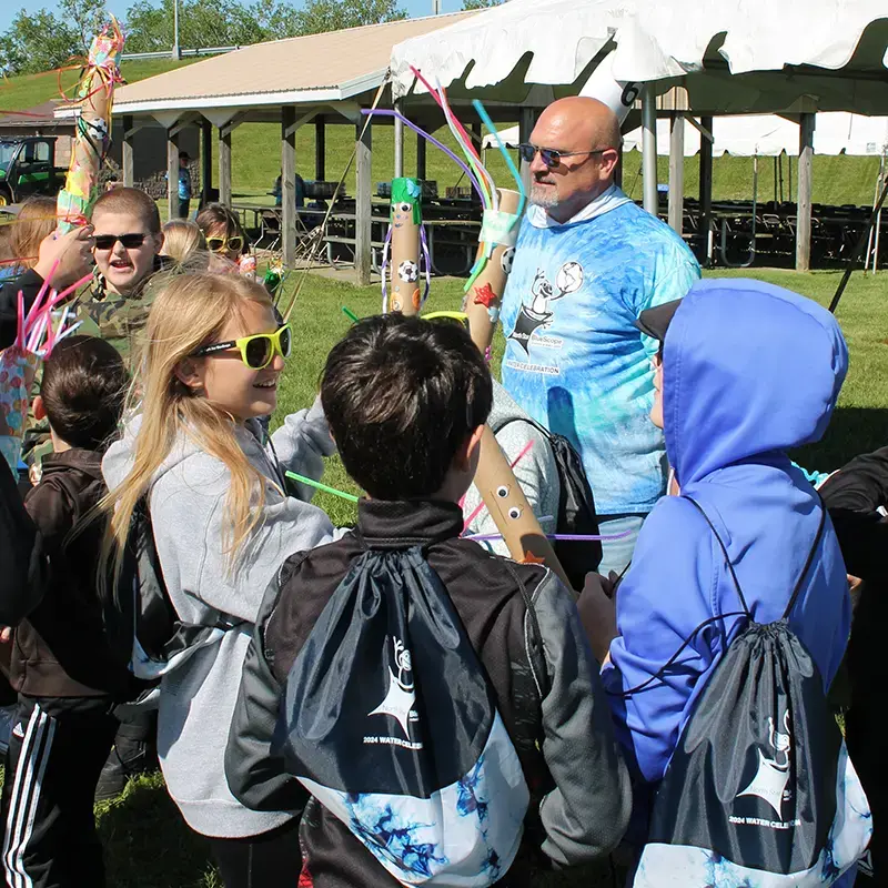Children and a North Star BlueScope Steel volunteer holding colorful craft projects made of tubes and pipe cleaners during the 2024 Water Celebration event.